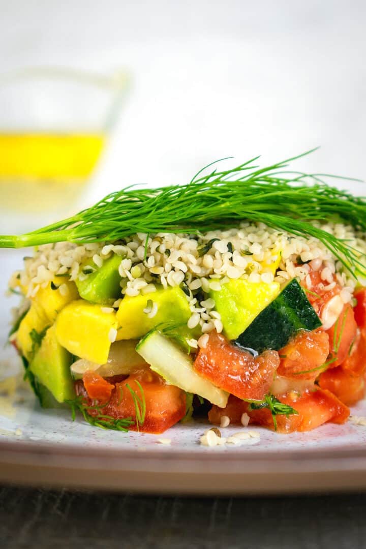Hemp seed salad stacked on plate with fresh dill sprig on top.
