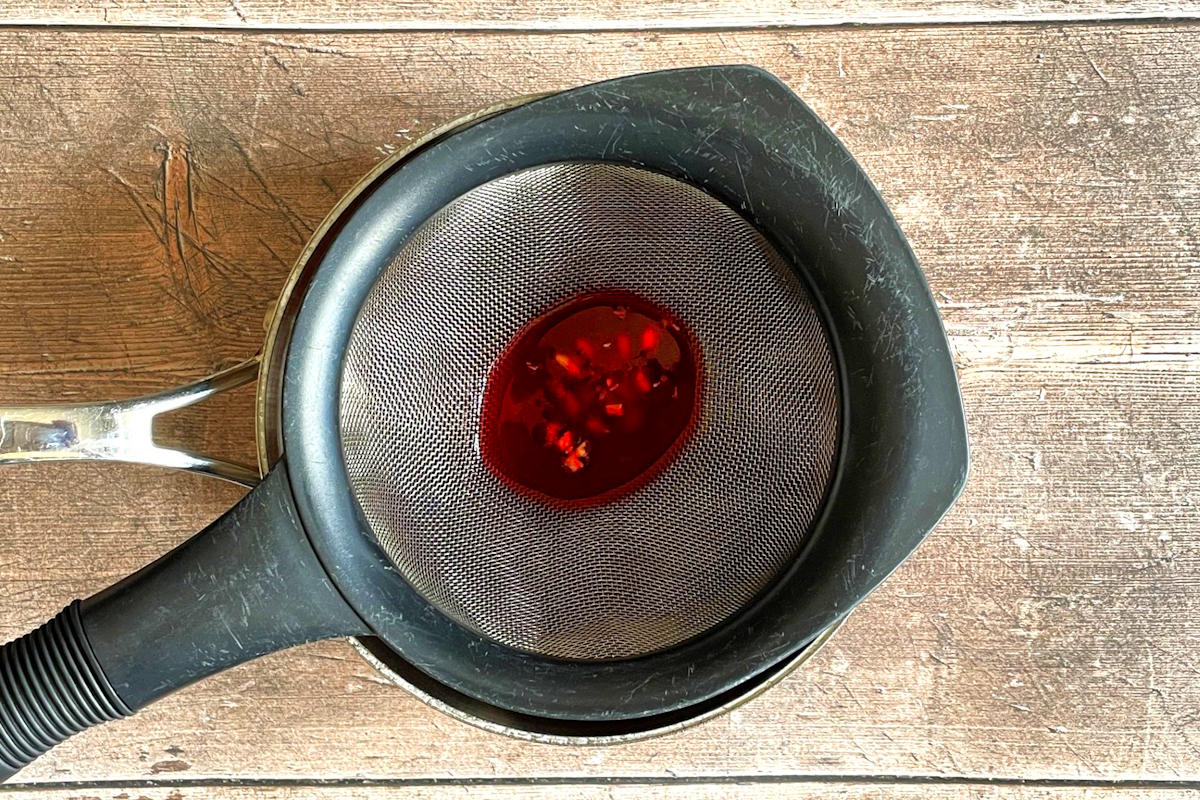 Freshly squeezed pomegranate juice in fine mesh strainer.