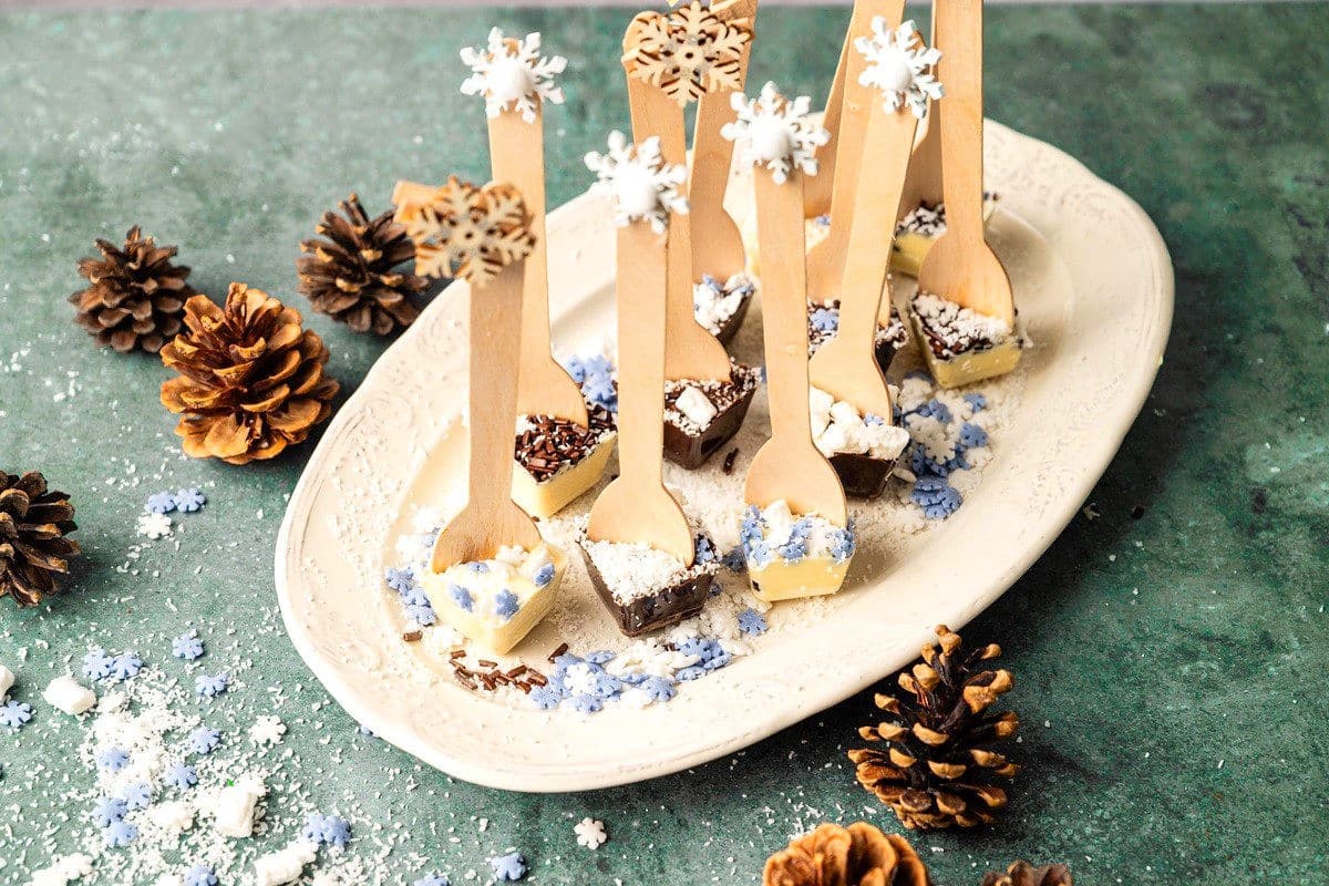 Hot chocolate spoons on white serving tray surrounded by acorns.