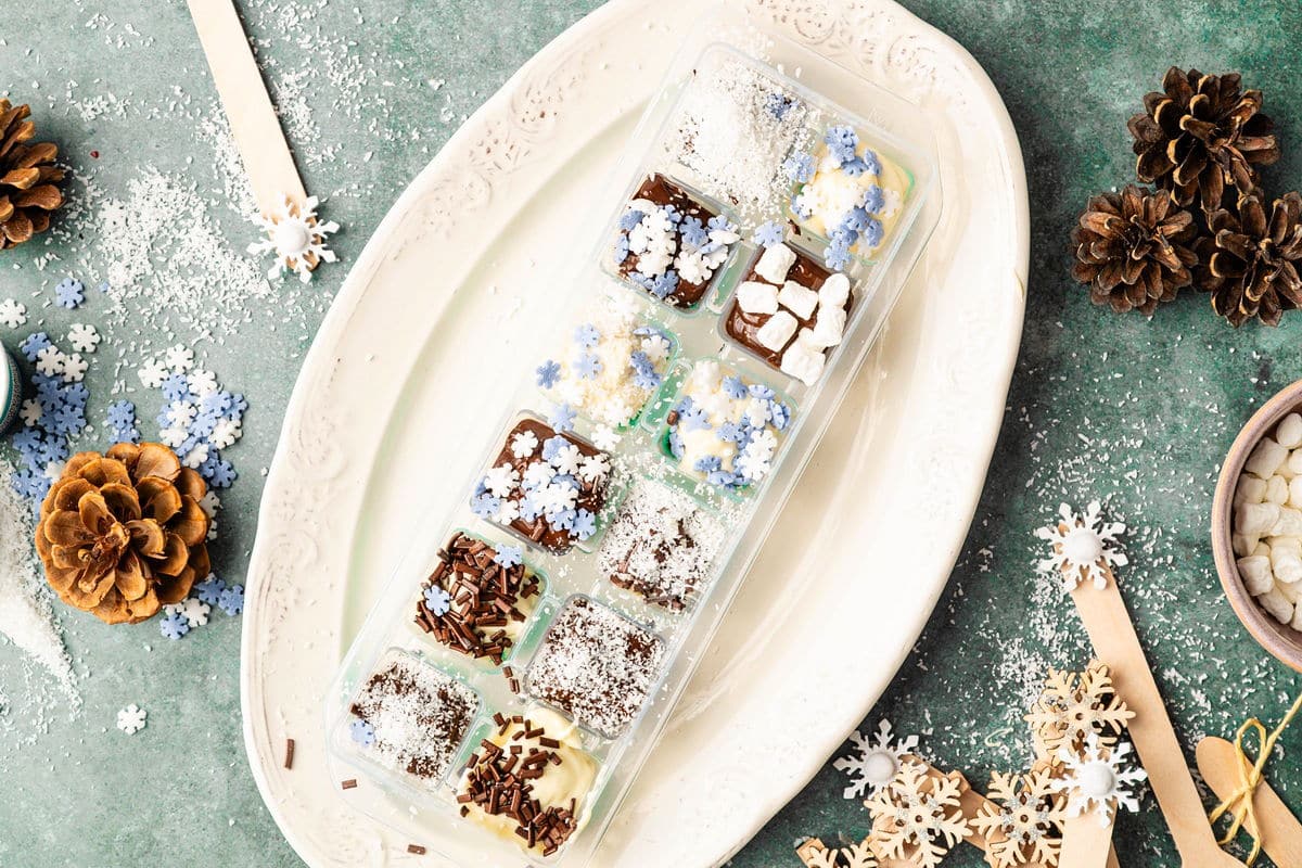 Chocolate sprinkled with toppings in ice cube tray.