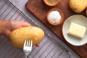 Russet potato in hand with fork.