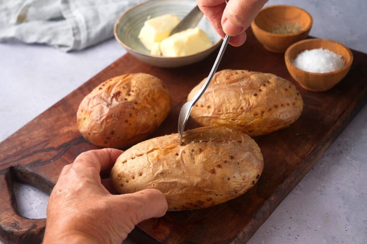 Fork piercing baked potato.