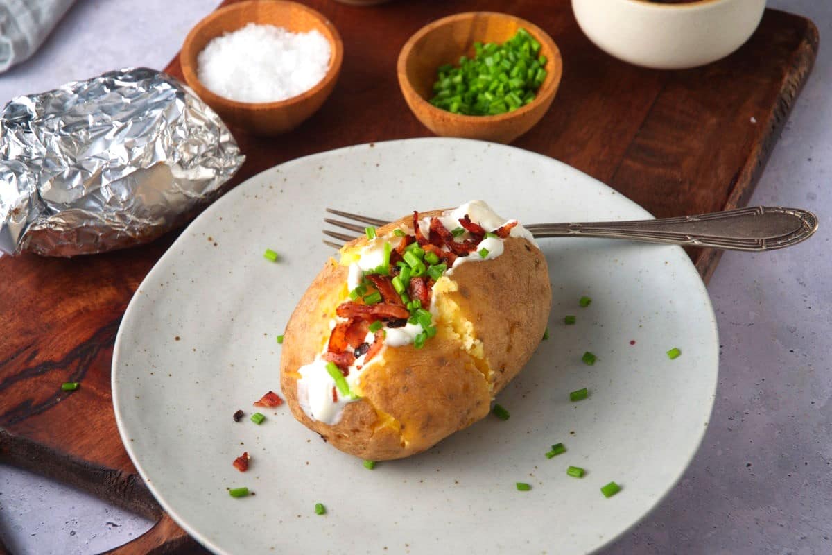 Loaded yellow potato on plate with fork.