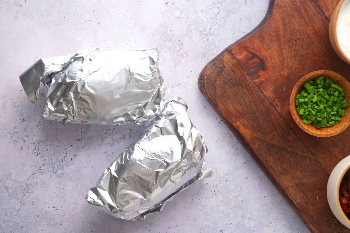 Potatoes in foil on marble counter.
