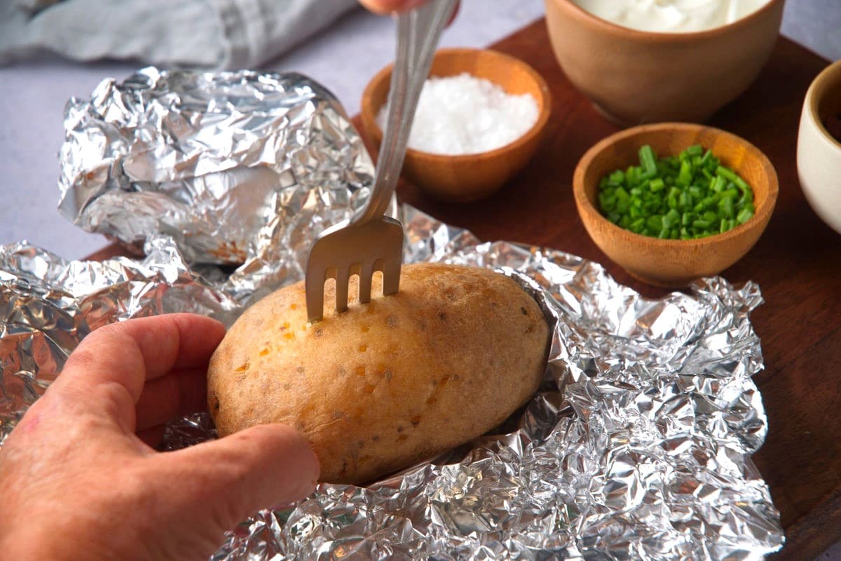 Baked Yukon Gold potato with fork in it.