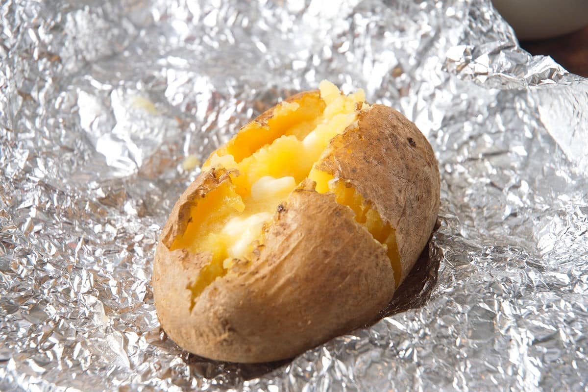 Baked potato on foil with butter.