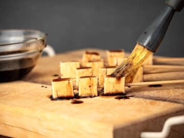 Cubed tofu on cutting board with soy sauce mixture.