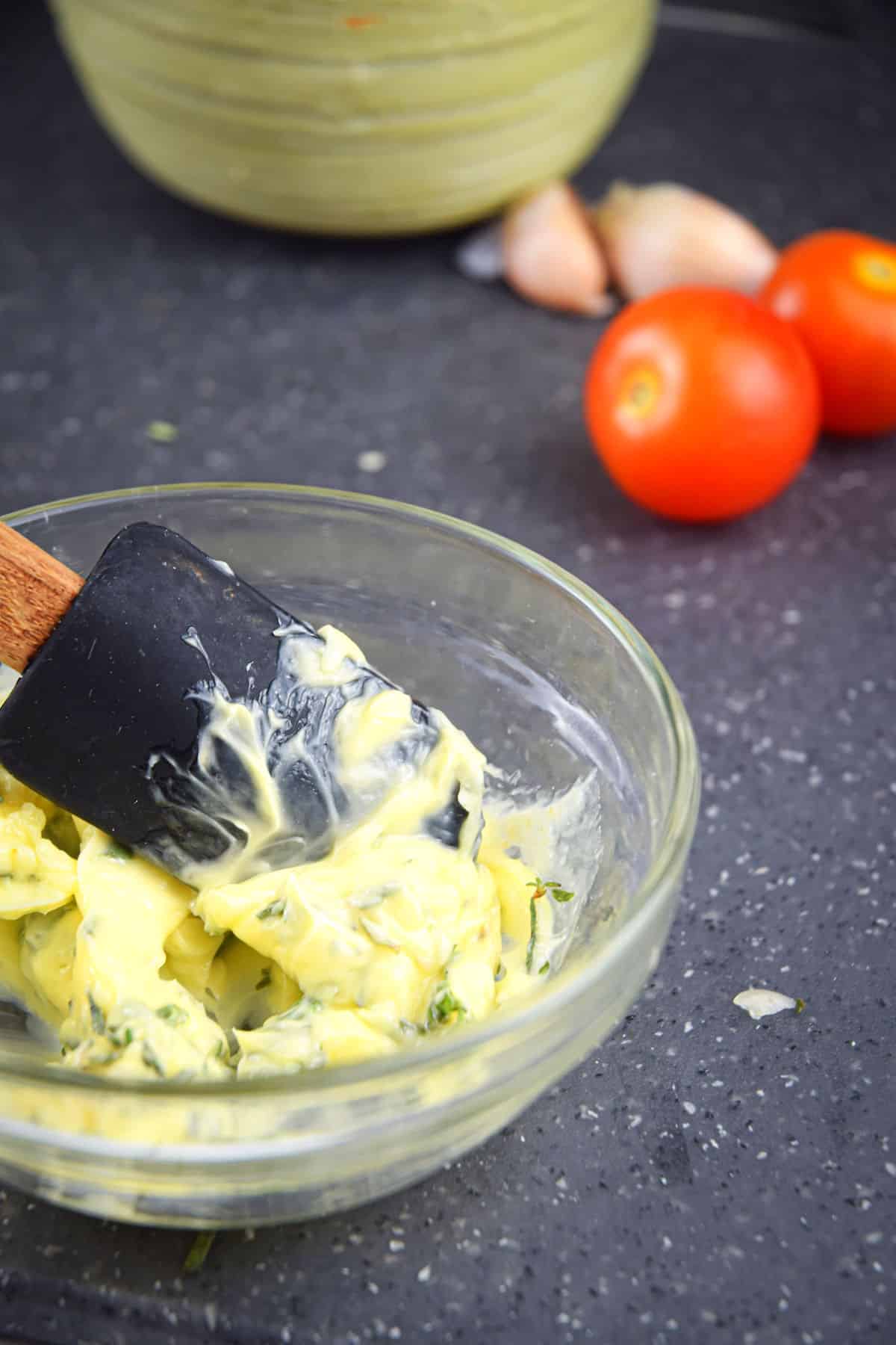 Garlic and herb butter in bowl with spatula.