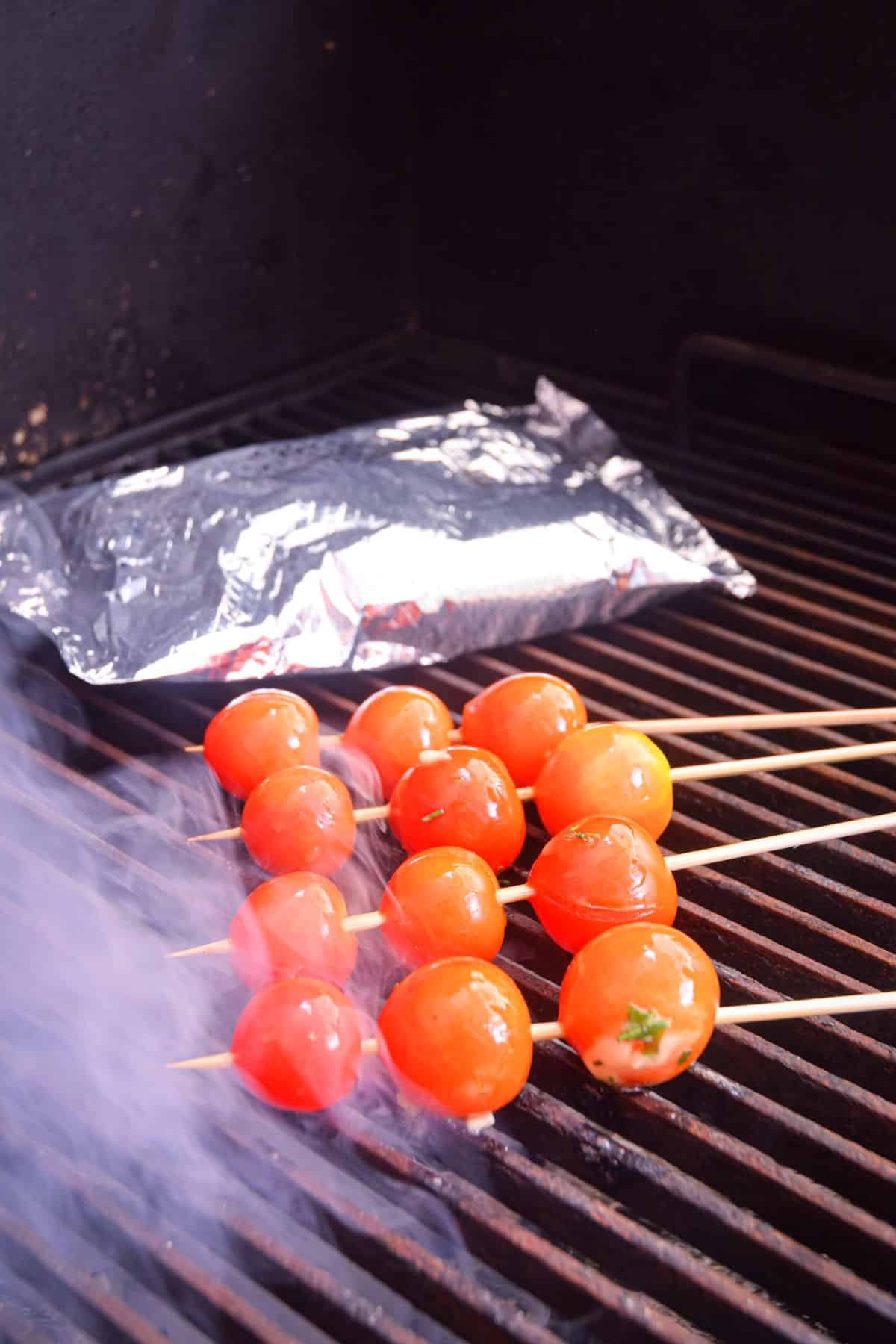 Cherry tomatoes grilling on skewers.