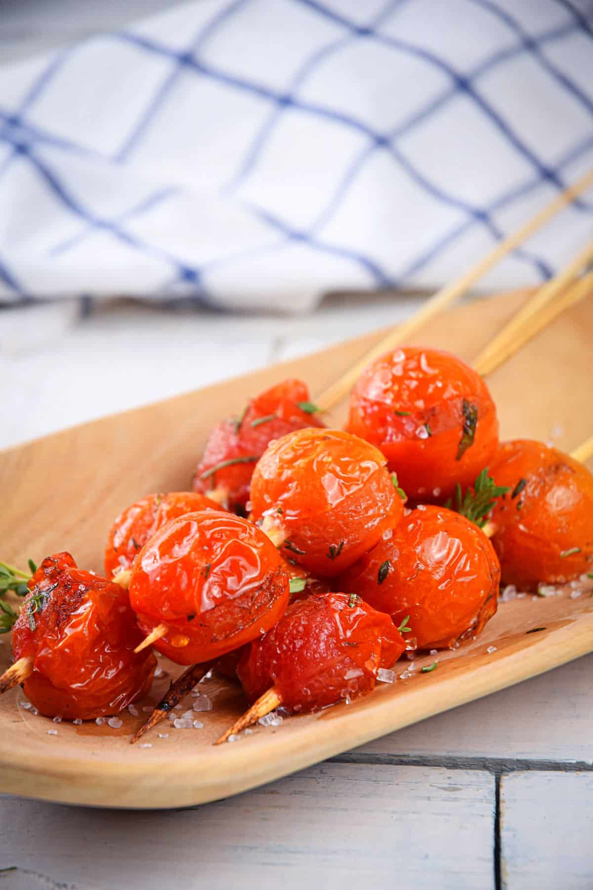 Grilled cherry tomatoes on wooden serving tray.