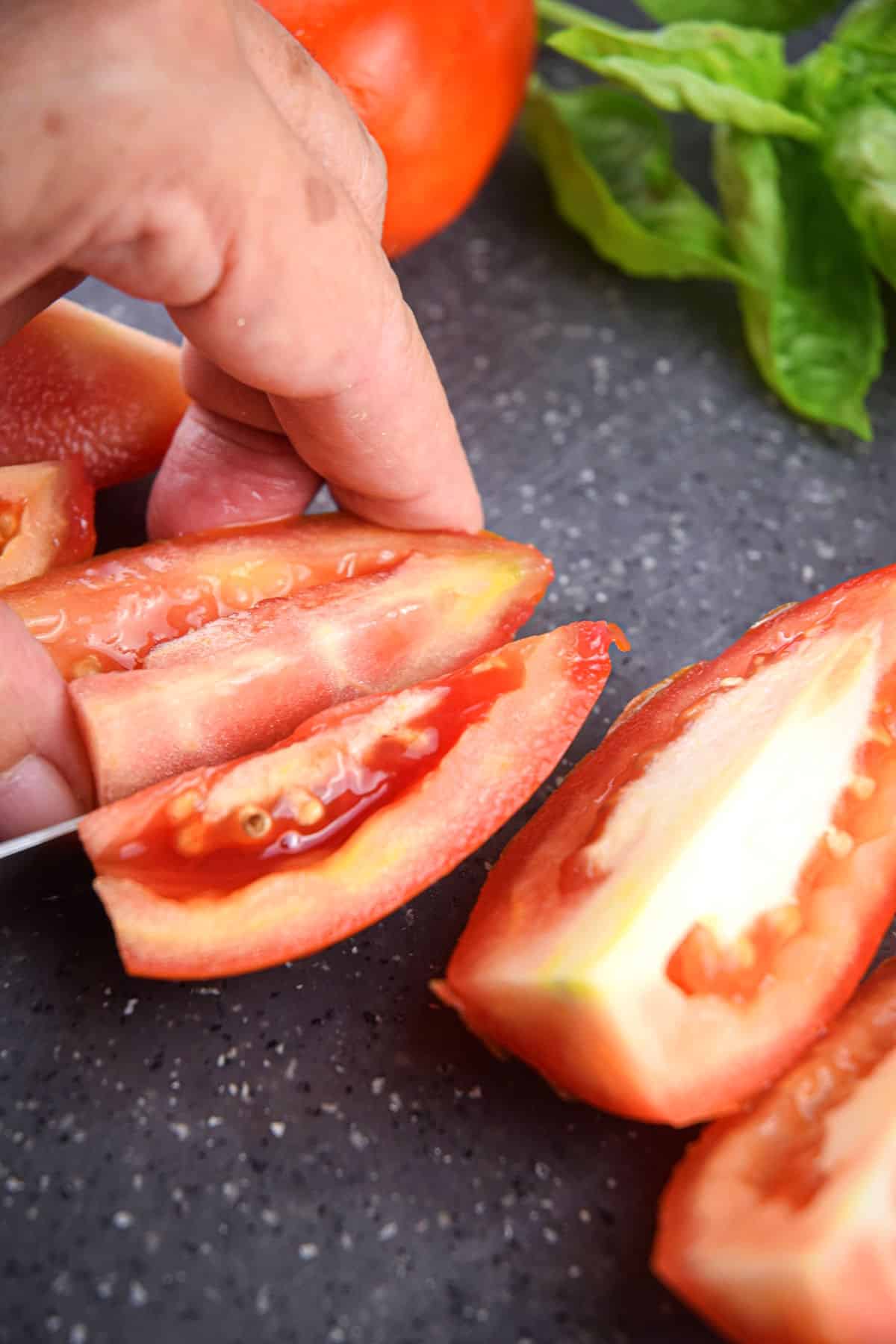 Roma tomatoes sliced on cutting board.