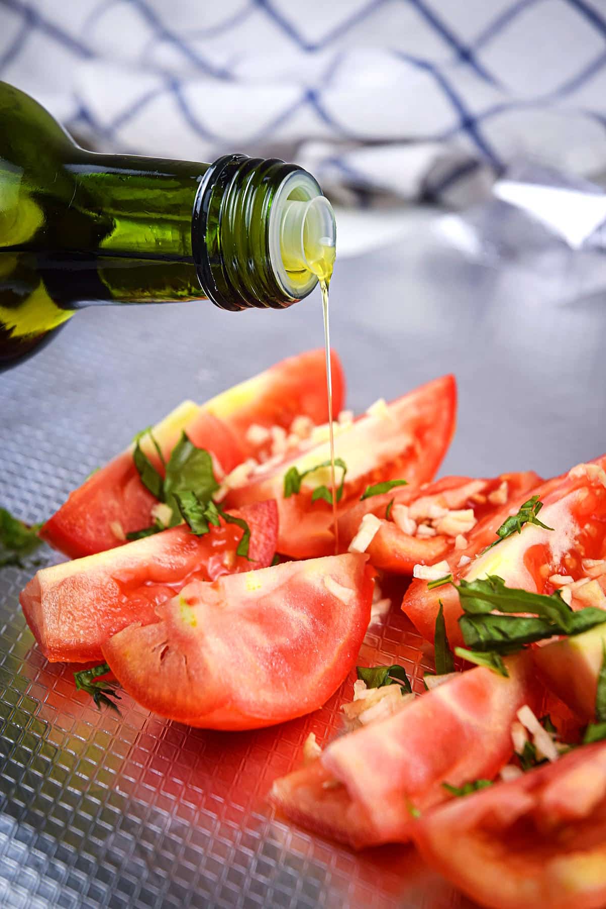 Olive oil drizzling over sliced Roma tomatoes.