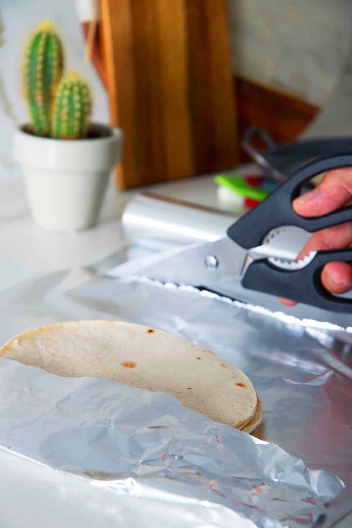 Stack of corn tortillas on foil with scissors.