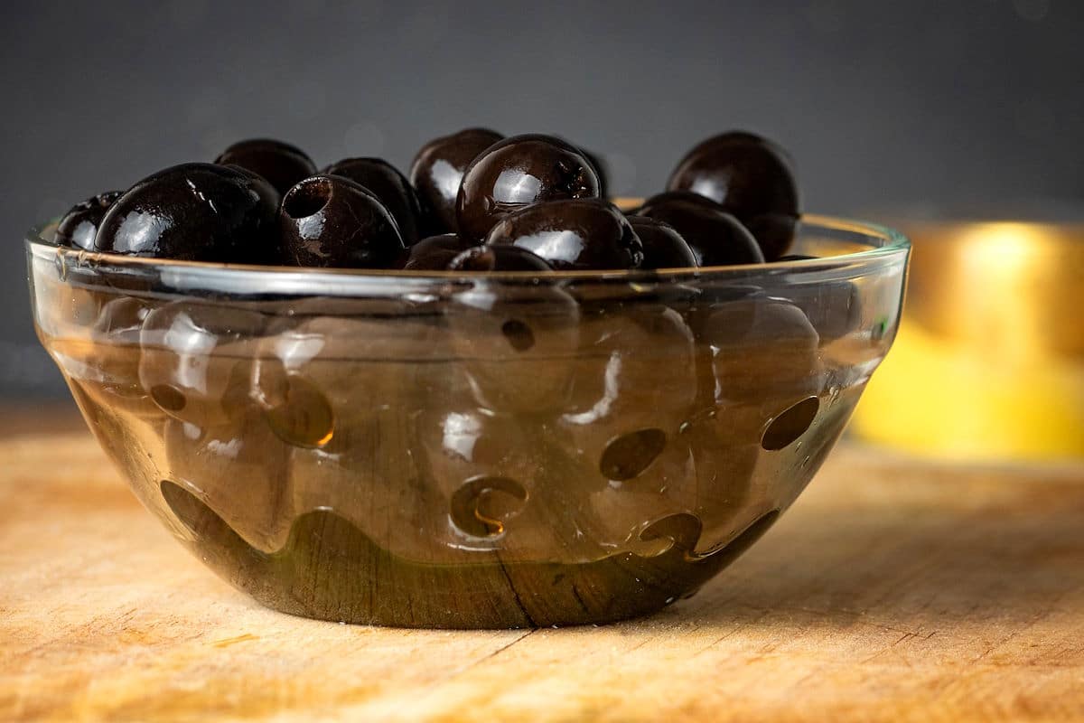 Black olives on wooden board.