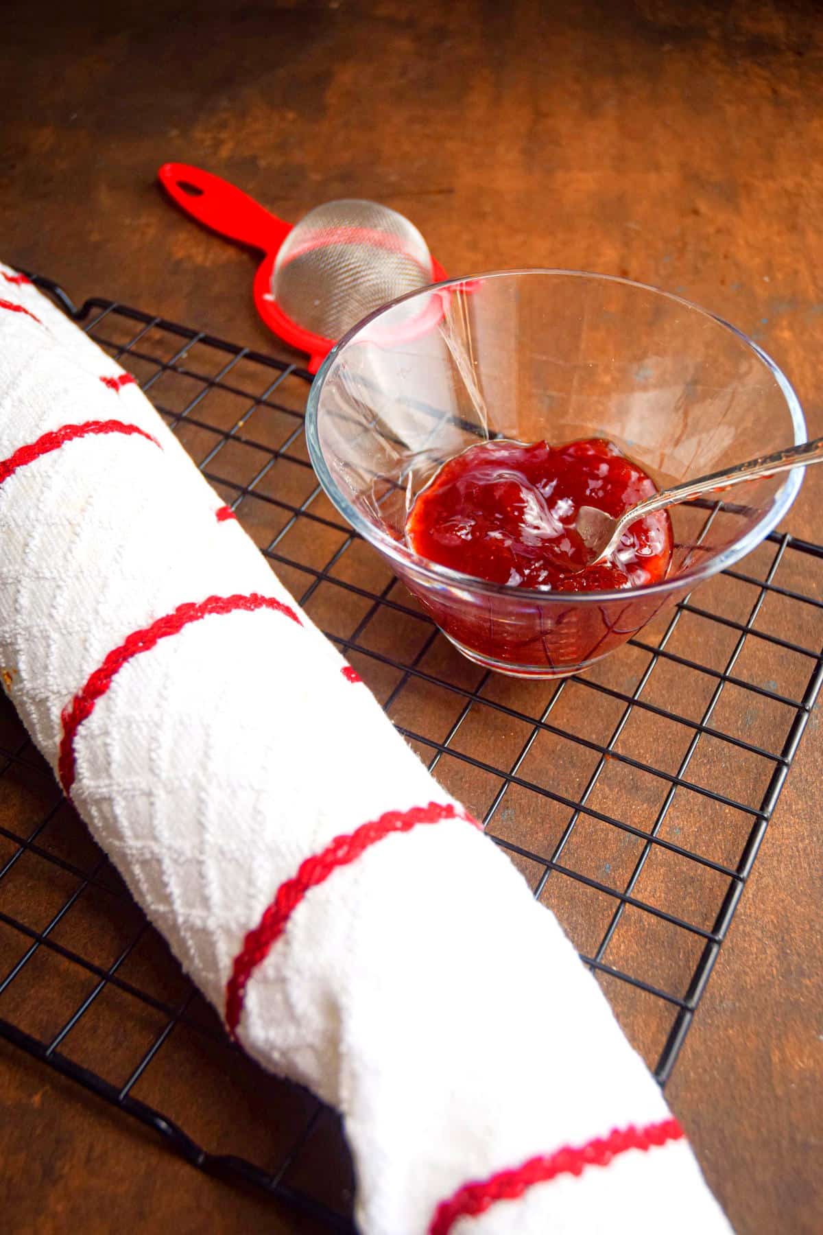 Jelly roll cake in towel on baking rack.