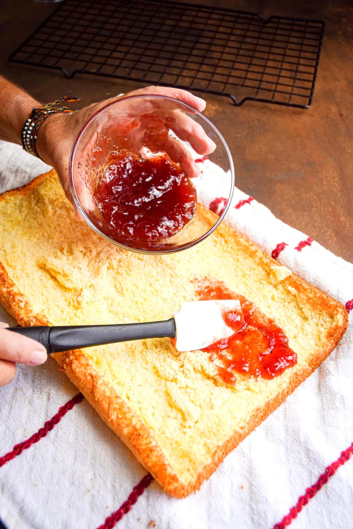 Jelly roll cake getting filled with strawberry jelly.
