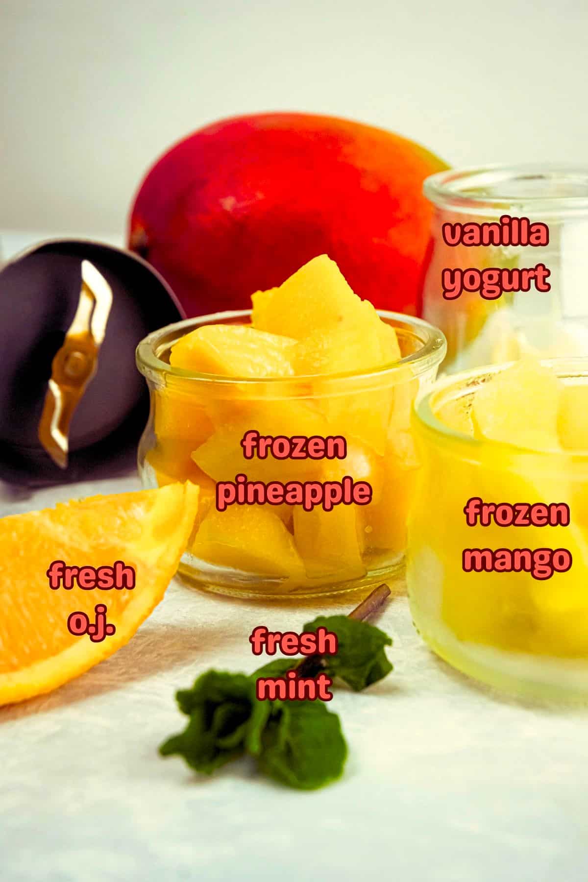 Mango pineapple smoothie ingredients prepped on light background.