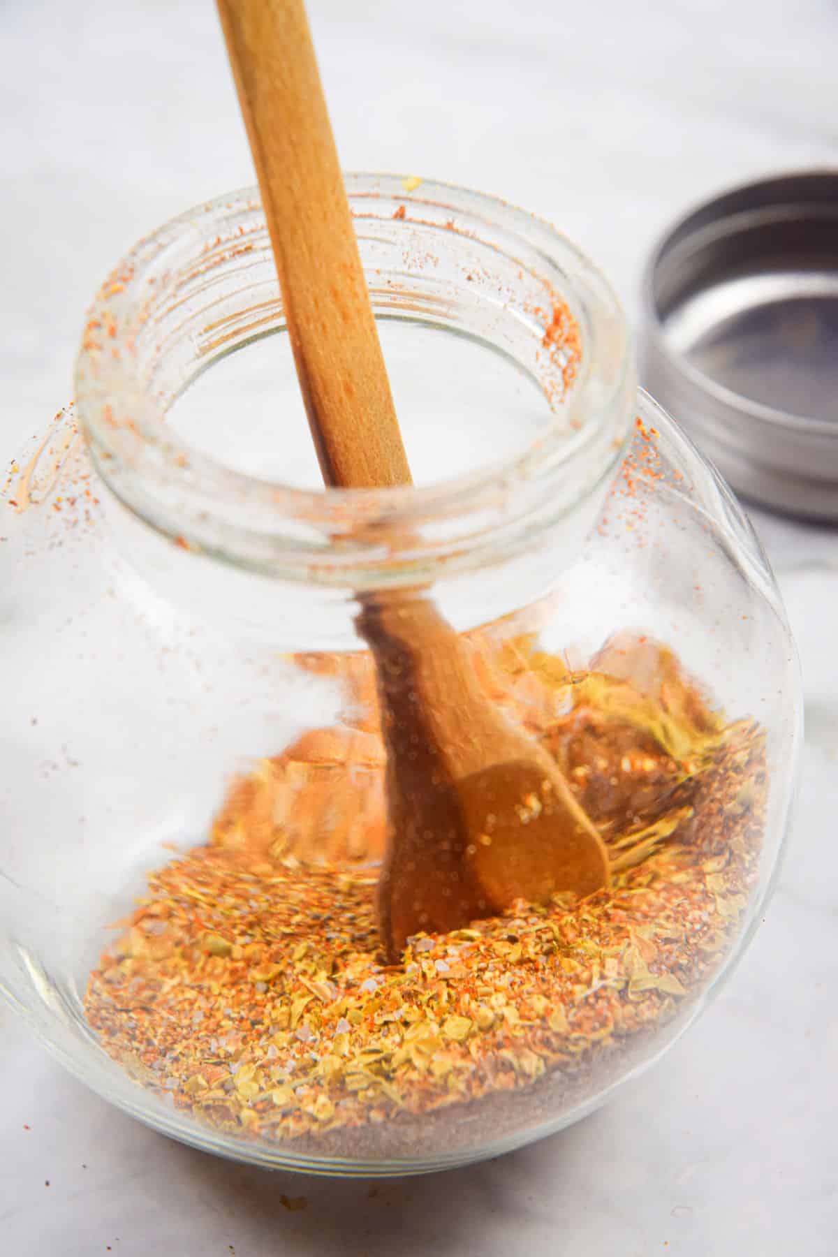 Cajun seasoning in small jar with wooden spoon.