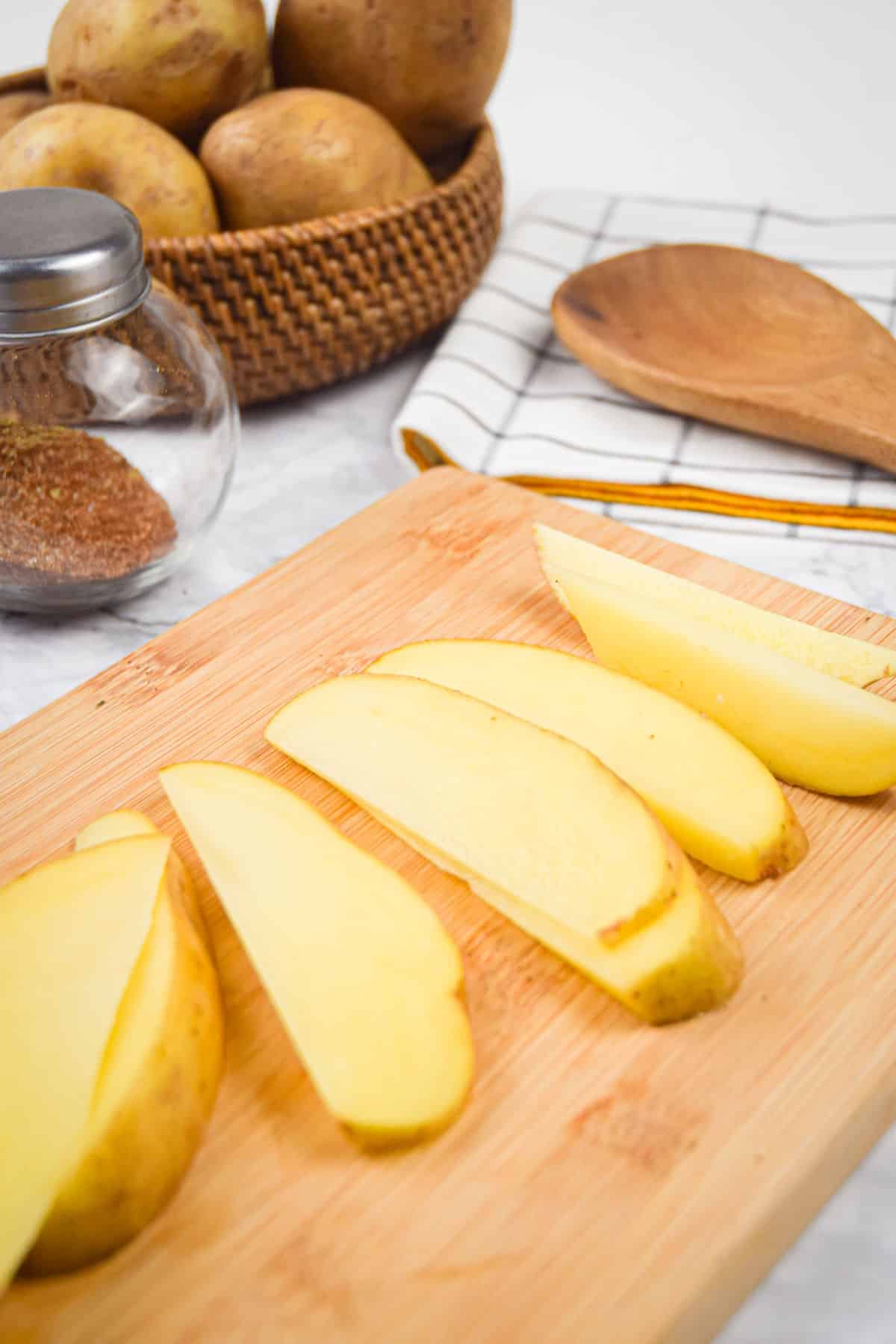 Potato wedges on cutting board.