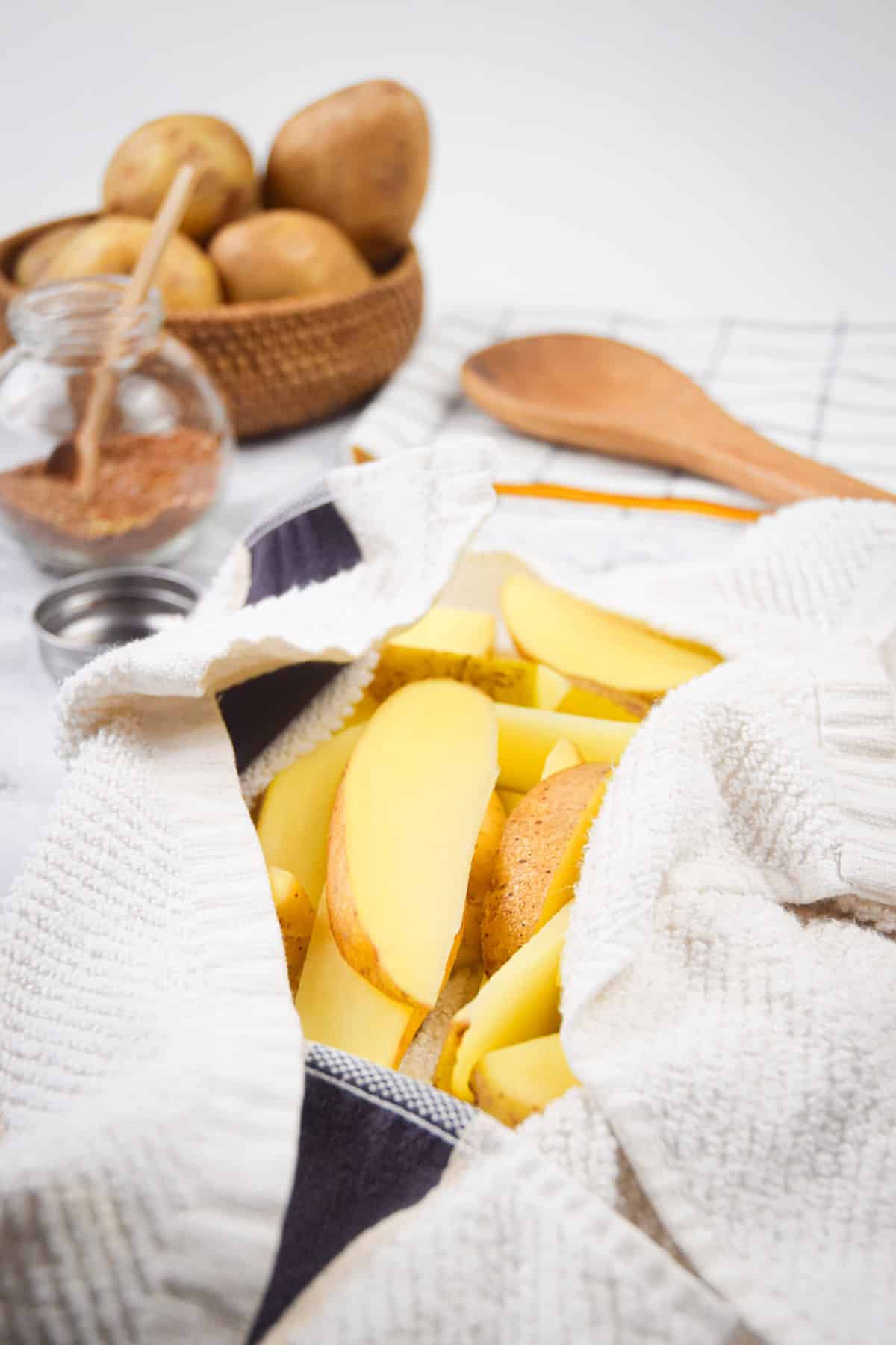 Potato wedges drying in clean kitchen towel.