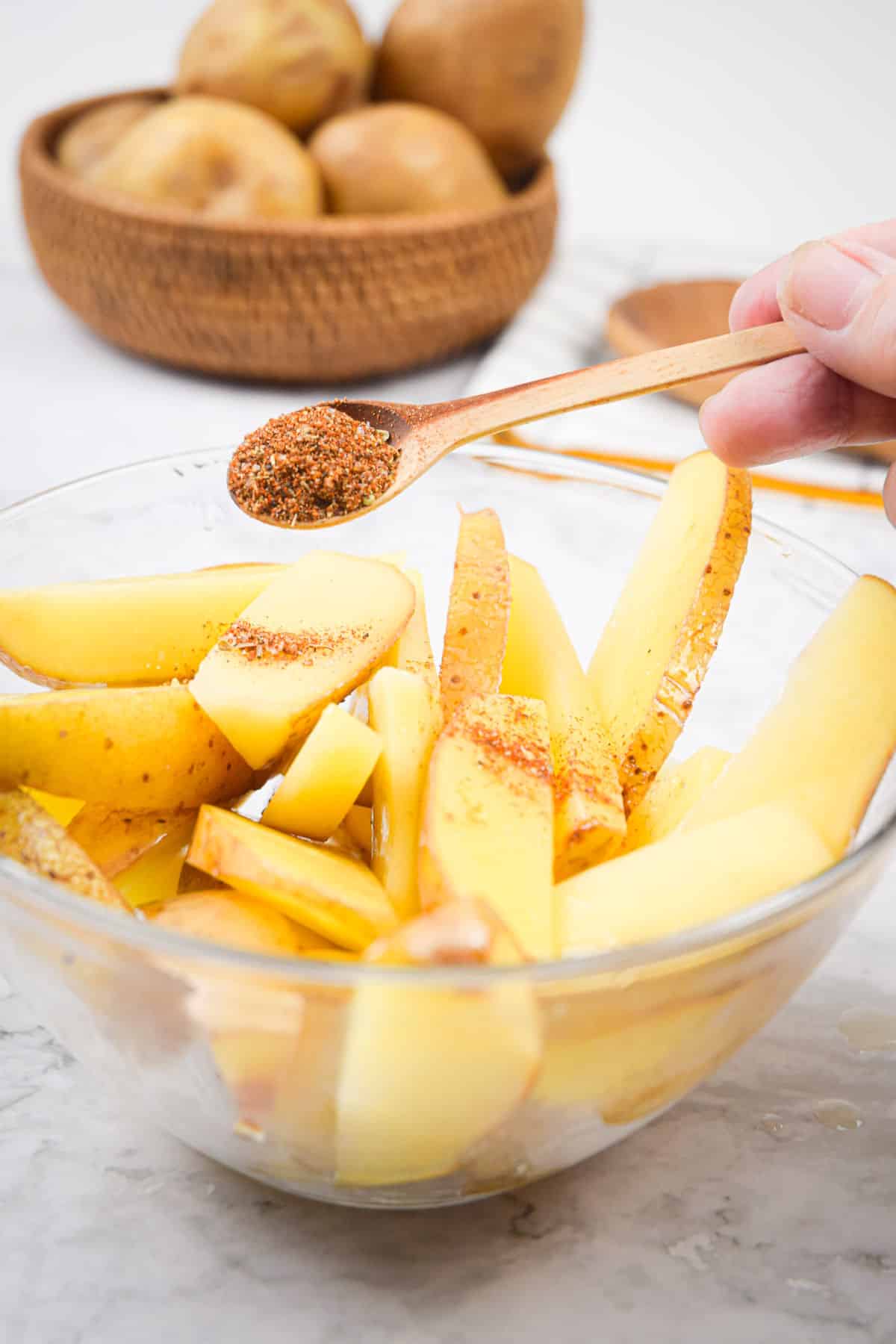 Potato wedges in bowl with Cajun seasoning.