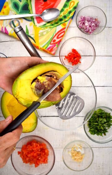 Avocado cut open with a knife in it.