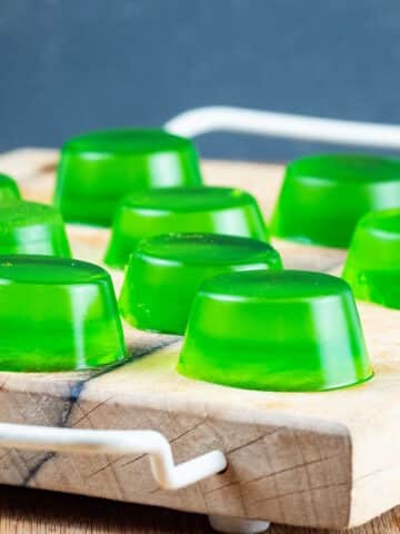 Green homemade gummies on cutting board.