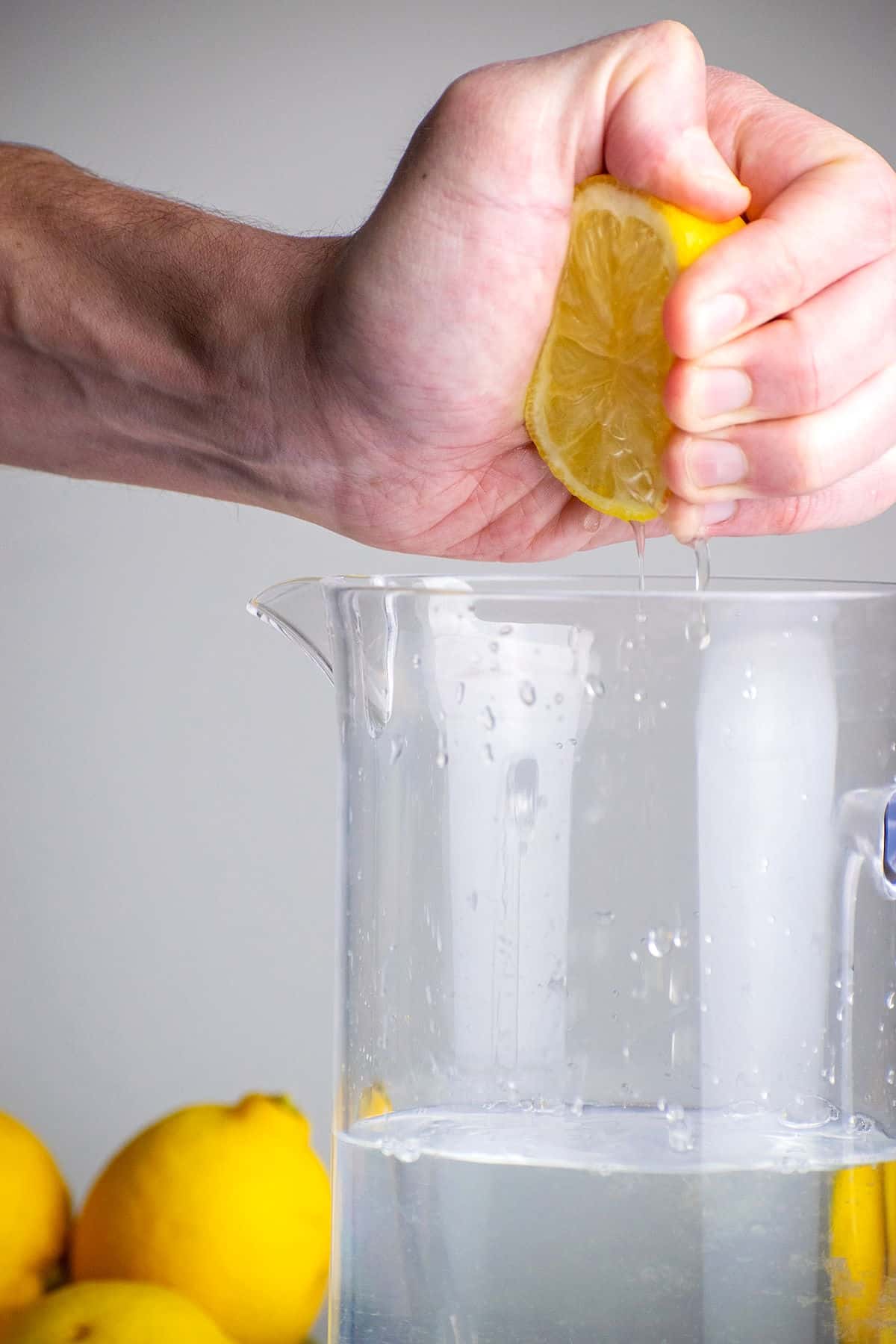 Lemon getting squeezed into pitcher of water.