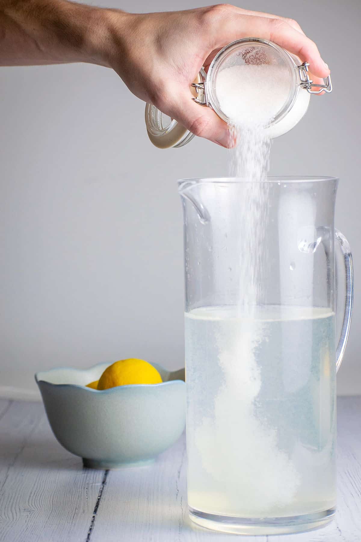 Sugar pouring into pitcher of water.