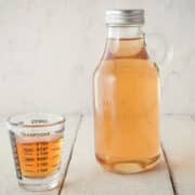 Simple syrup in bottle and small measuring cup.