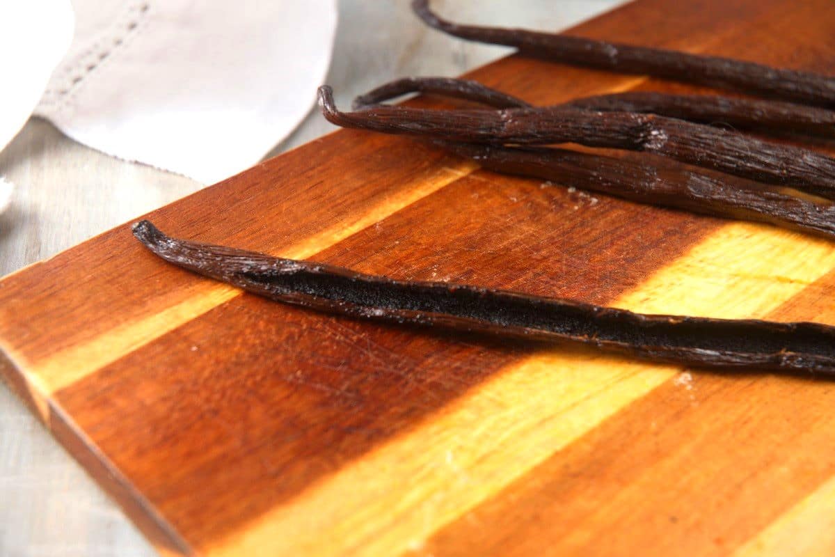 Vanilla beans split open on cutting board.