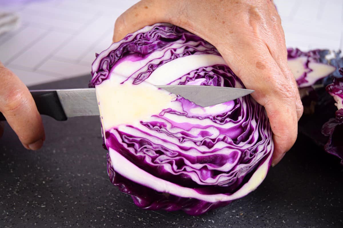 Red cabbage getting cored with knife.