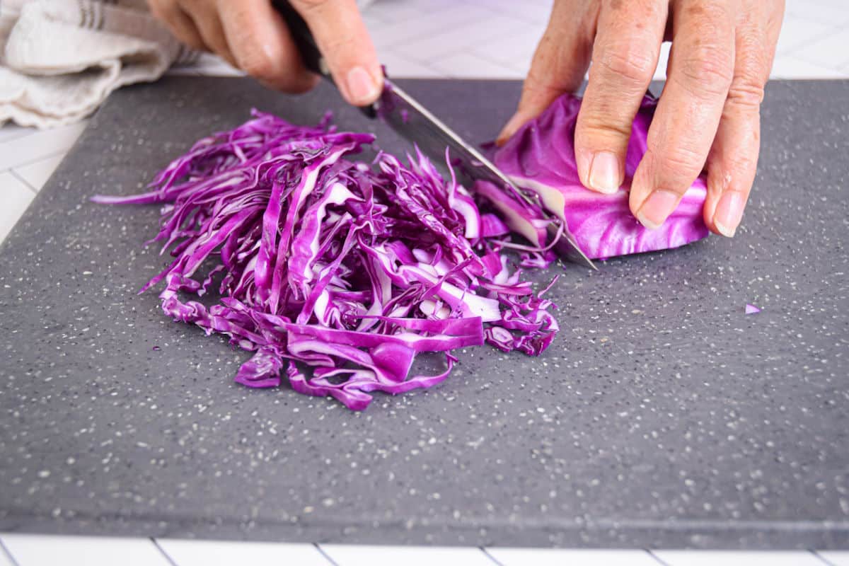 Red cabbage getting shredded with knife.