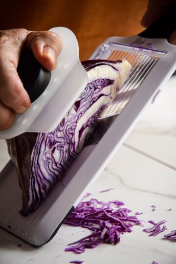 Red cabbage against mandolin with hand guard.
