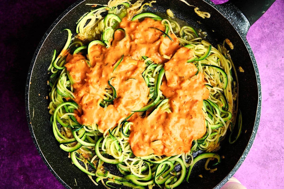 Zucchini noodles (zoodles) with creamy tomato sauce in pan.