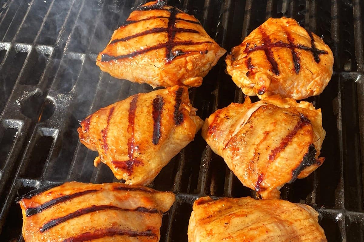 Kimchi chicken on the grill with grill marks.
