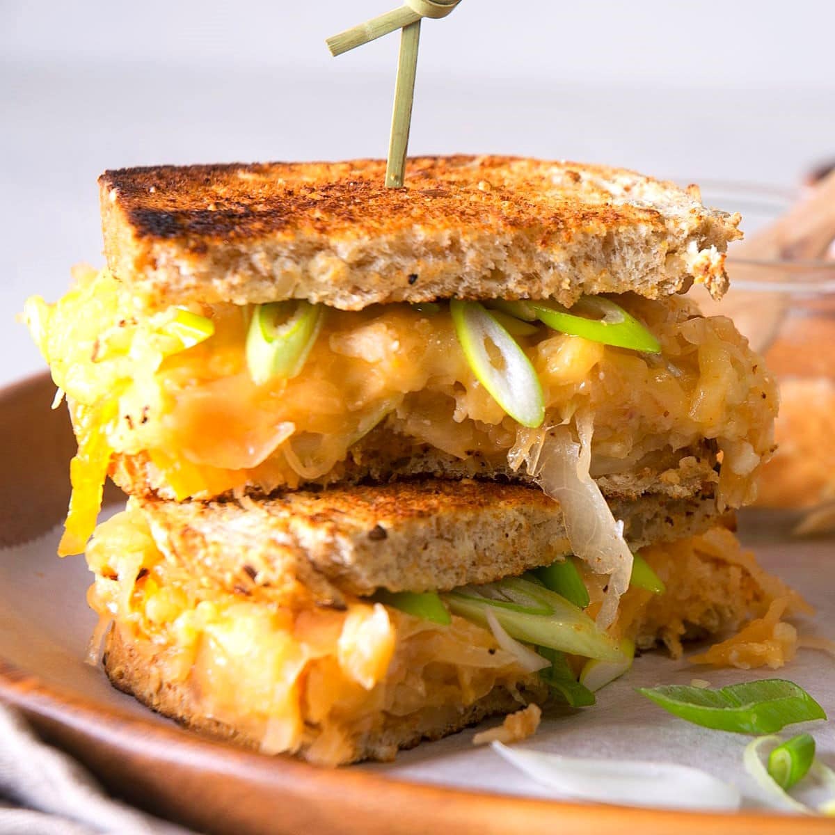 Kimchi grilled cheese sandwiches stacked on serving tray with skewer.
