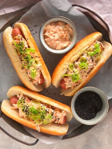 Kimchi hot dogs with small bowls of toppings on serving tray.