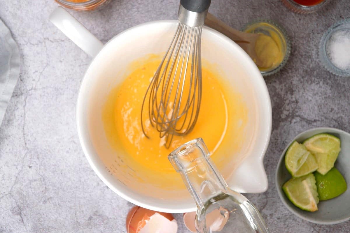 Homemade mayo being prepared in bowl with whisk.
