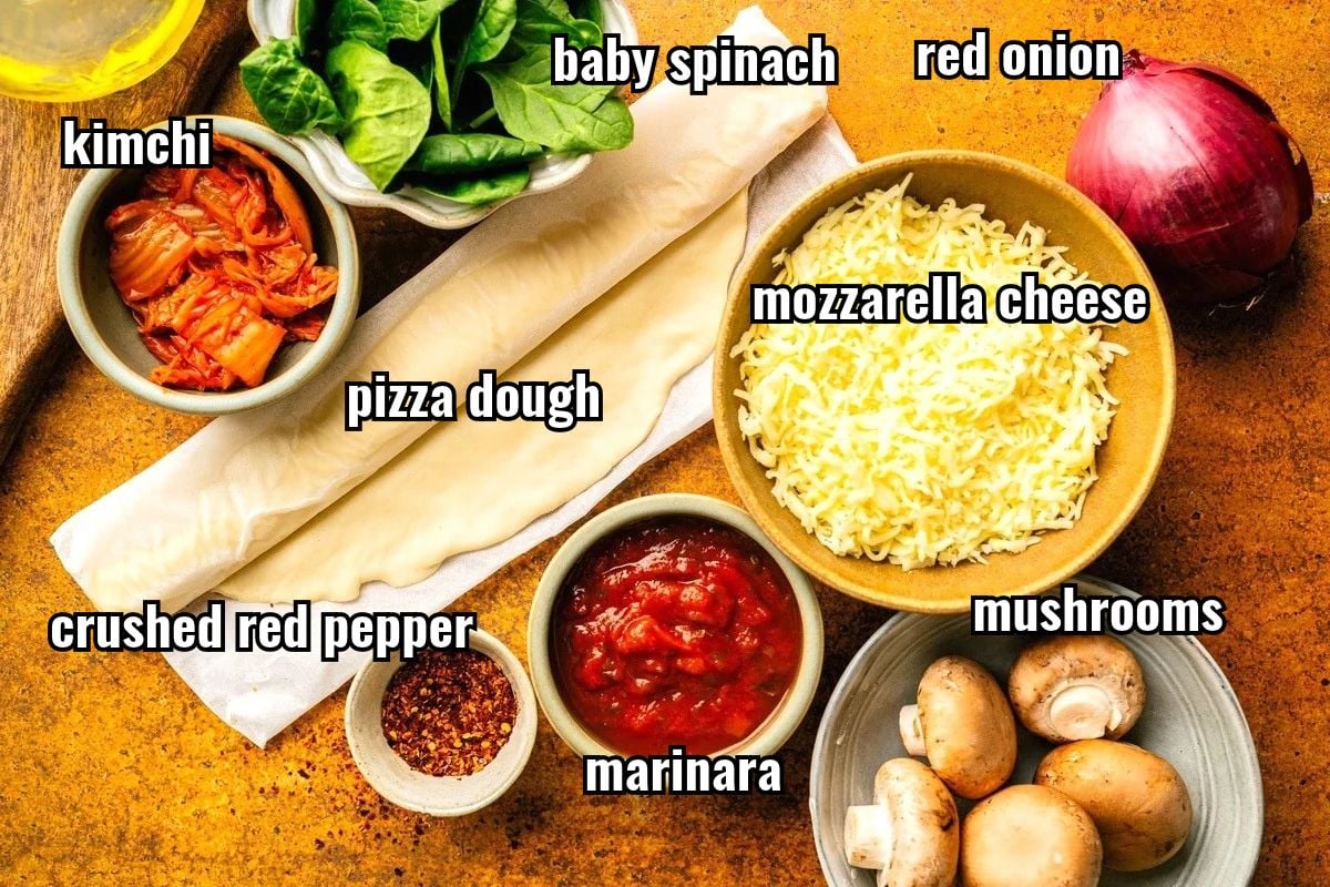 Kimchi pizza ingredients labeled on orange background.