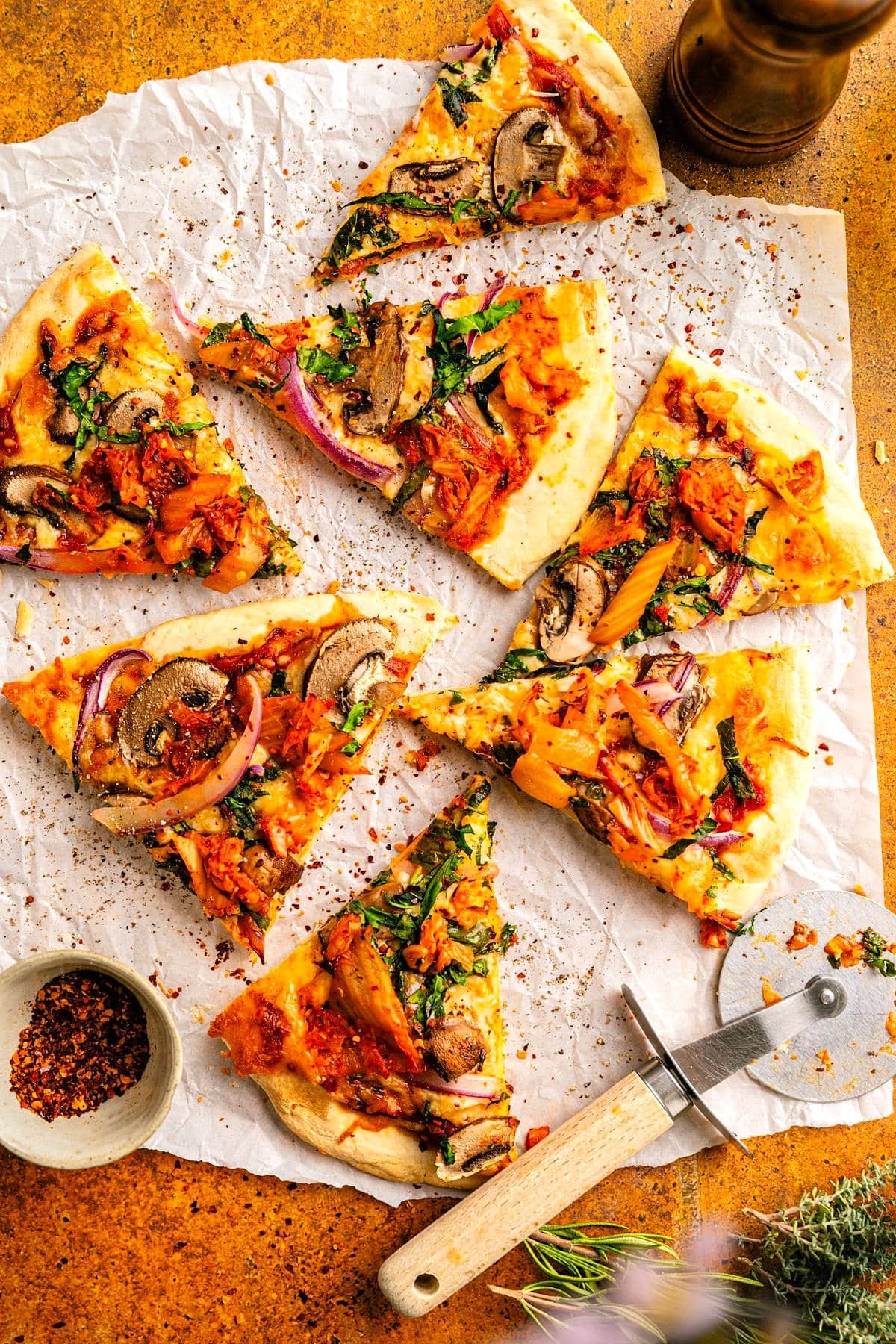 Kimchi pizza sliced on parchment paper.