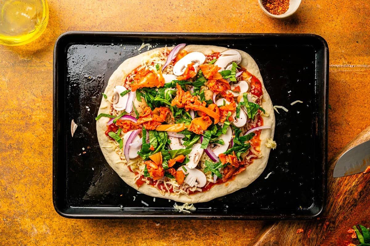 Kimchi pizza toppings on pizza dough.