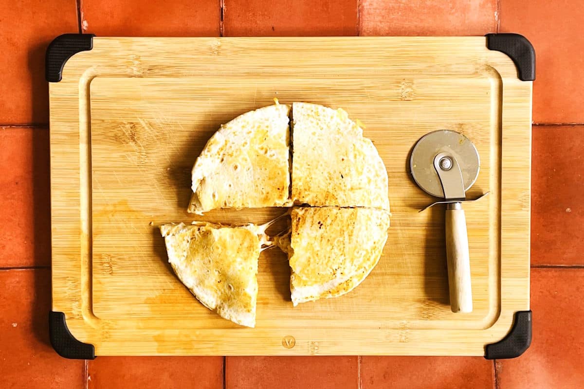 Pan-fried kimchi quesadilla sliced on cutting board.