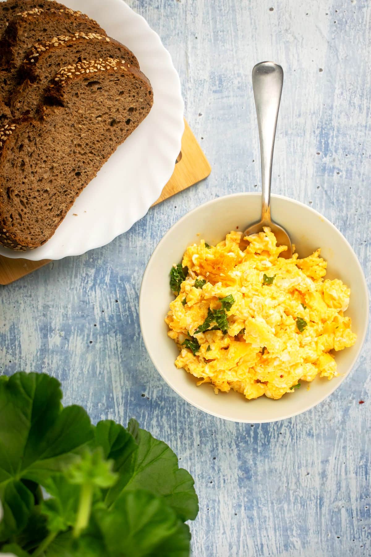Korean kimchi scrambled eggs in bowl with dark rye bread on the side.