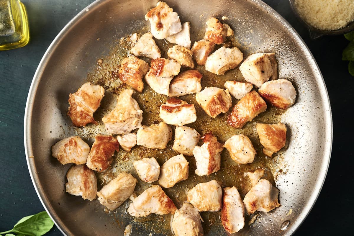 Fried chicken breast cubes in pan.