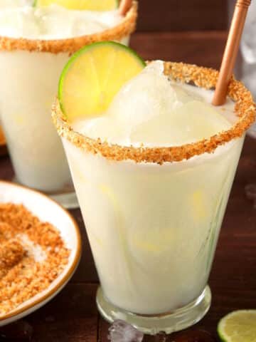 Lime cremosa drink in a glass with straw and lime slice.