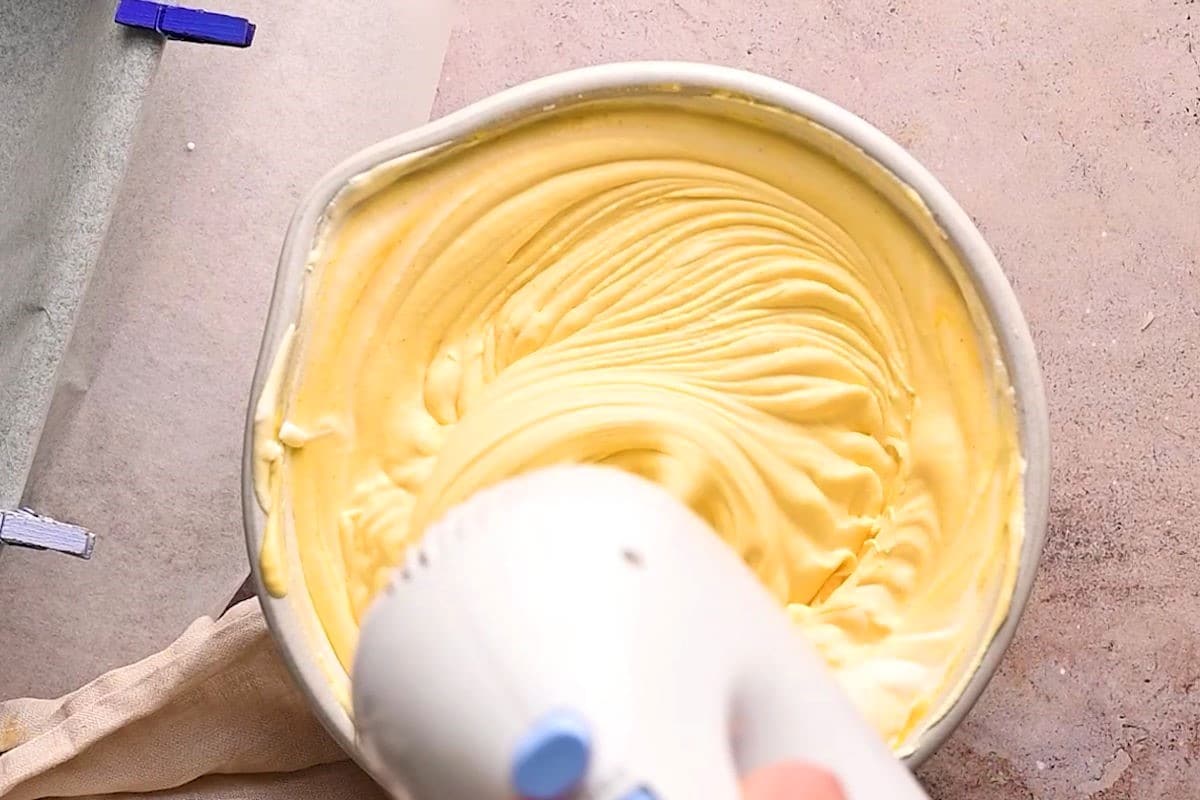 Mac and cheese ice cream whipped in bowl with electric mixer.