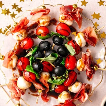 Mini caprese skewers arranged on plate with NYE decorations on the side.