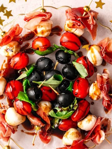 Mini caprese skewers arranged on plate with NYE decorations on the side.