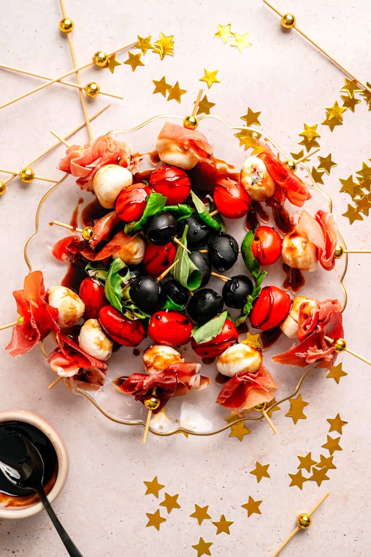 Mini caprese skewers on a clear plate.